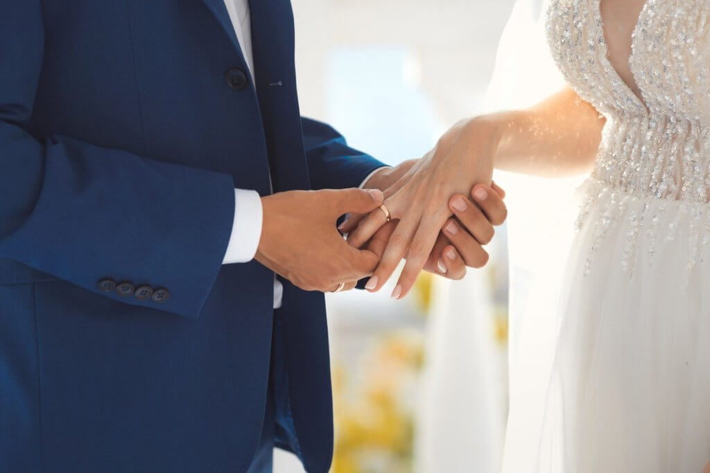 Die Braut steckt ihrem Bräutigam den Ring an den rechten Finger.