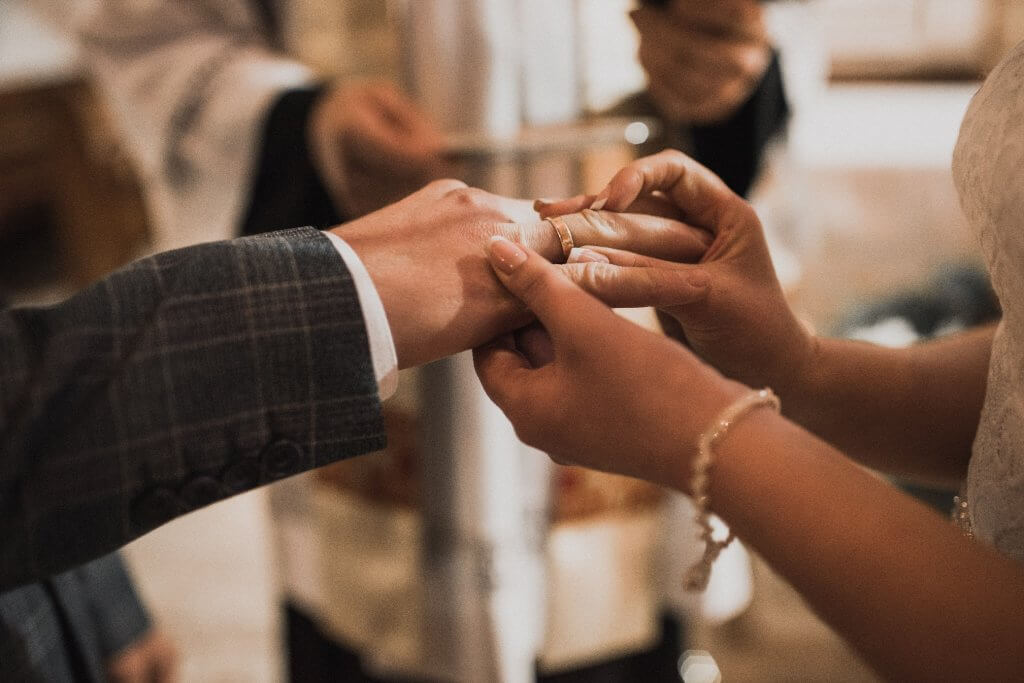 Die Braut steckt ihrem Bräutigam den Ring an den rechten Finger.